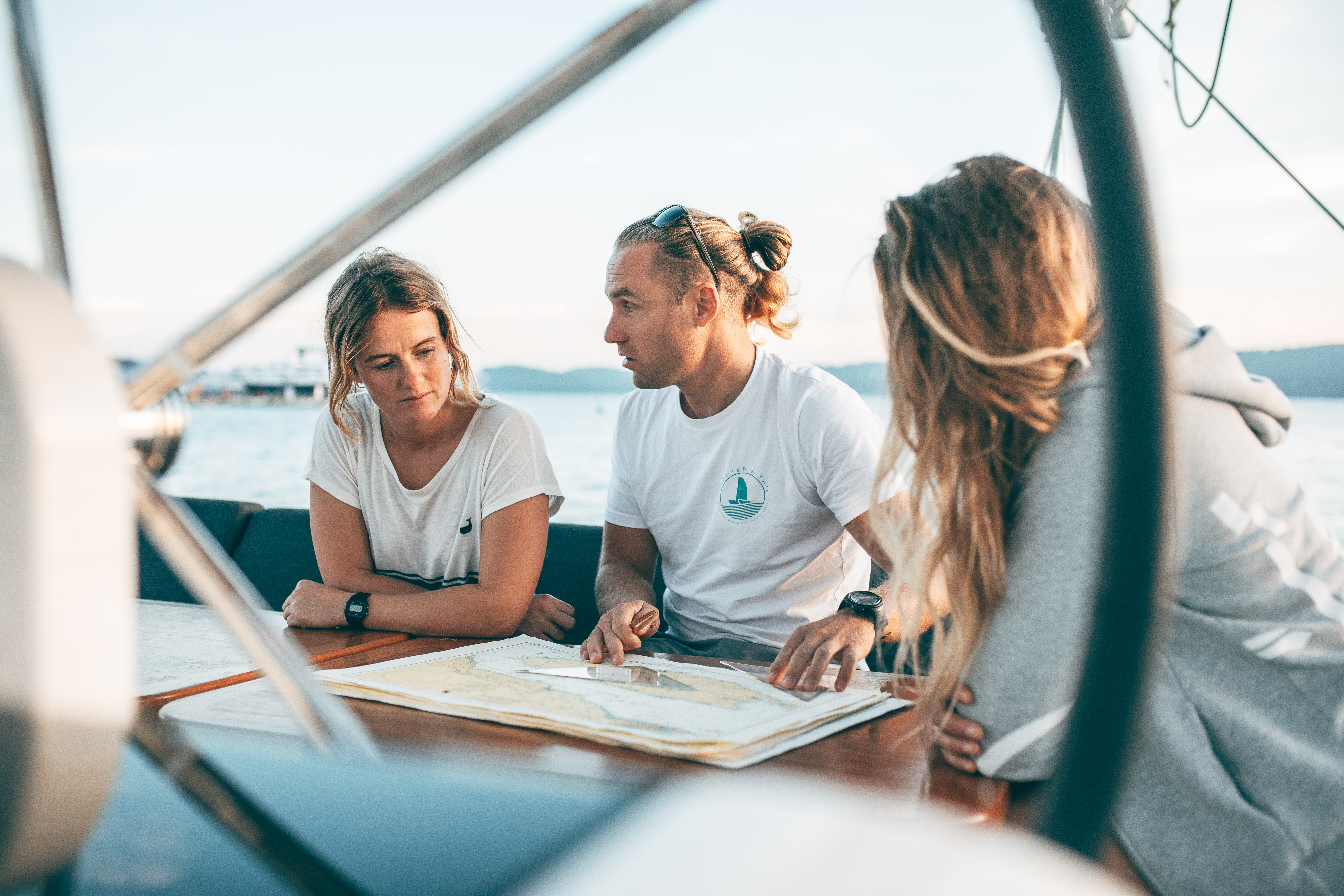Fotoshooting auf dem Wasser mit Charter & Sail / Segel Shooting / Personen vor Seekarte auf Katamaran